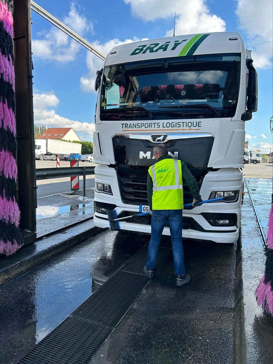 Personne en train de nettoyer un camion des Transports Bray à l'aide d'une brosse